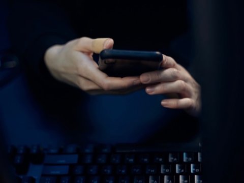 scammer hands with phone and keyboard